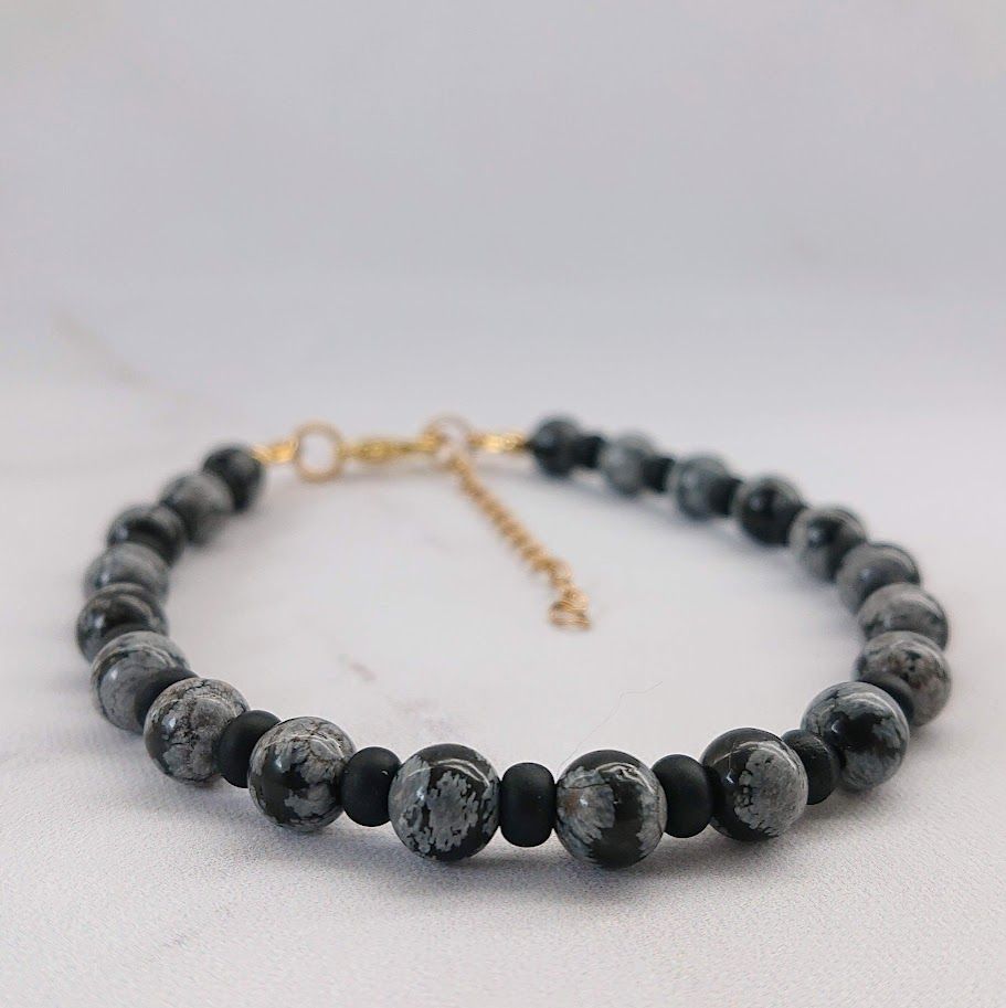 Chique armband van snowflake obsidiaan kralen van 6mm met matzwarte tussenkralen van 4mm en gouden stainless steel sluiting