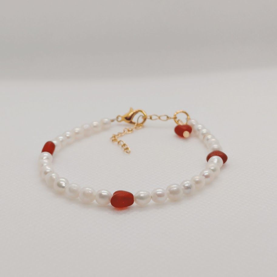Romantische armband van 4mm zoetwaterparles met rode hartjes en een gouden stainless steel sluiting met verlengketting