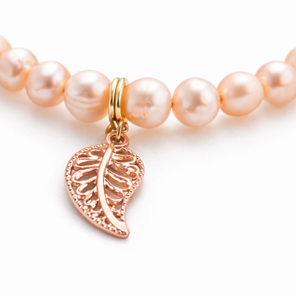 Handgemaakte armband met roze zoetwaterparels en goud/bronskleurige bladbedels met stainless steel afwerking