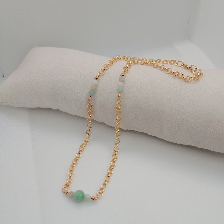 Stainless steel schakelketting met kleine amazoniet tussenkralen liggend op een kussentje