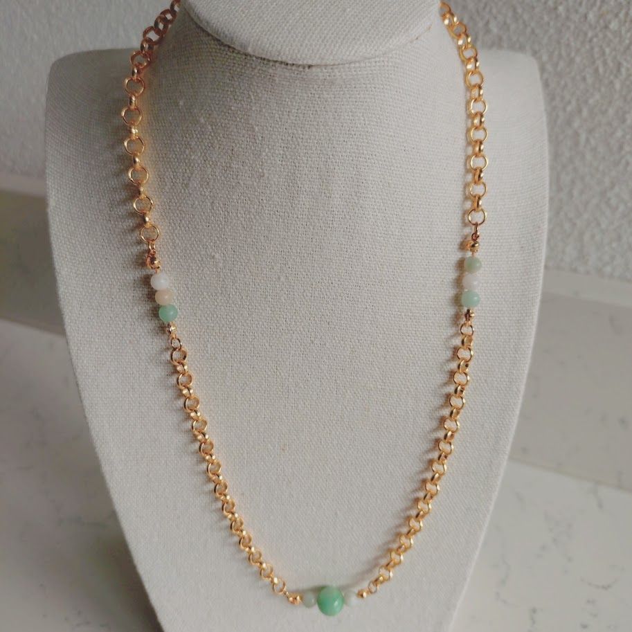 Stainless steel schakelketting met kleine amazoniet tussenkralen liggend op een kussentje