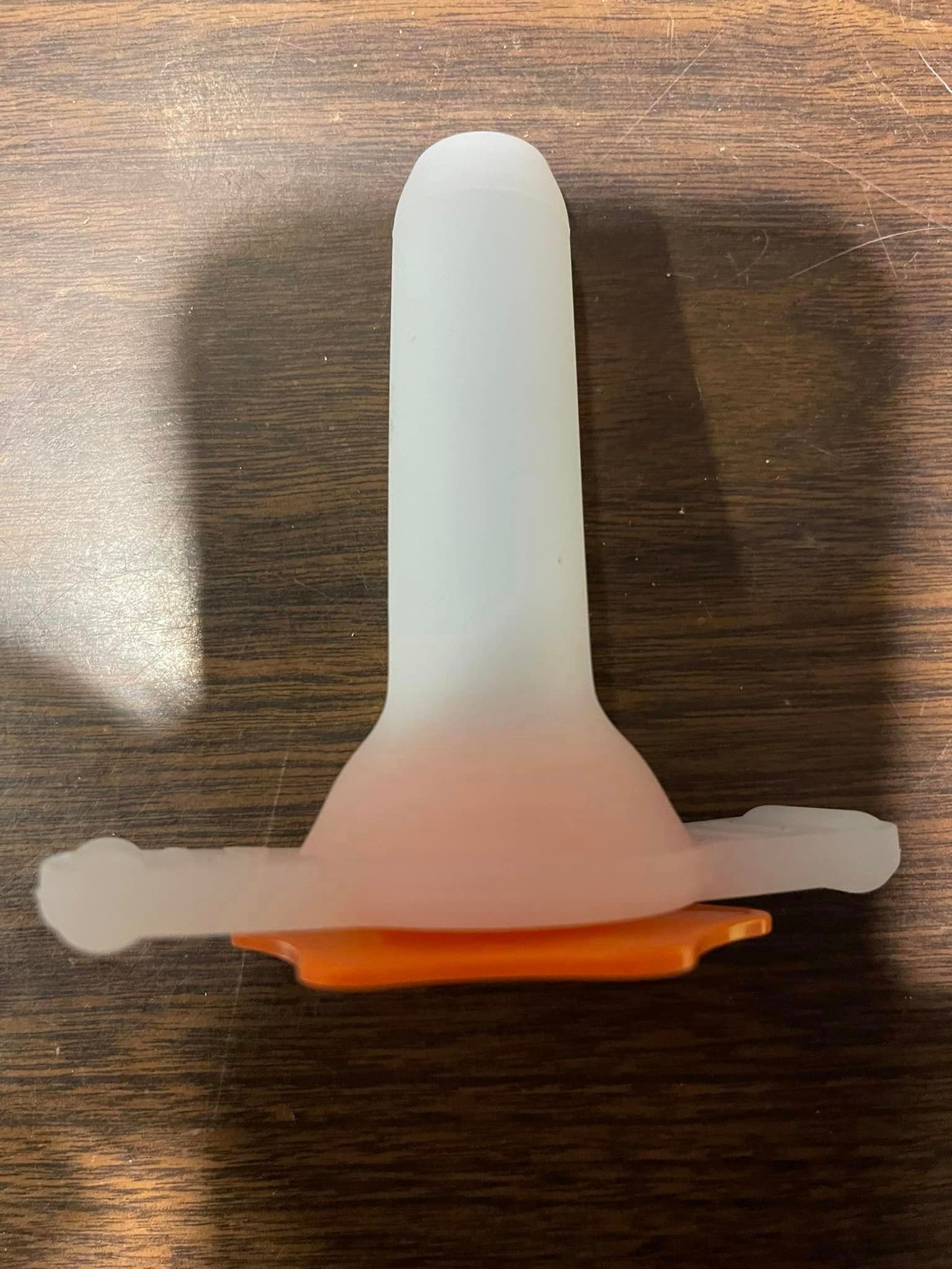 A white cone with an orange base is sitting on a wooden table.