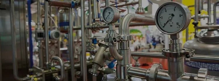 A bunch of stainless steel pipes and gauges in a factory.