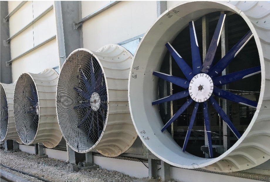 A row of fans are lined up on the side of a building