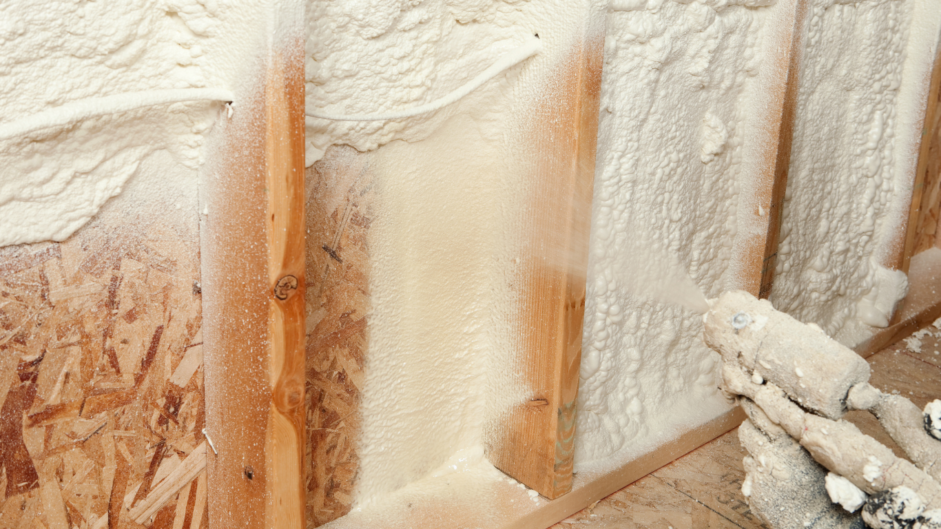 Technician carefully applying spray foam insulation to a wall panel, ensuring precise coverage for optimal energy efficiency and airtight sealing in County Limerick.