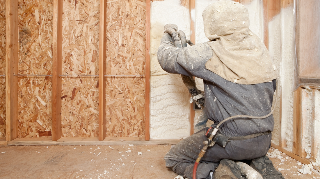 Professional technician spraying spray foam insulation onto attic panels, equipped with protective mask and gear for a safe and efficient installation in County Limerick.