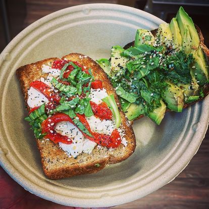 Two slices of toast with avocado and peppers on a plate