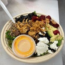 A bowl of food with a spoon and a dipping sauce