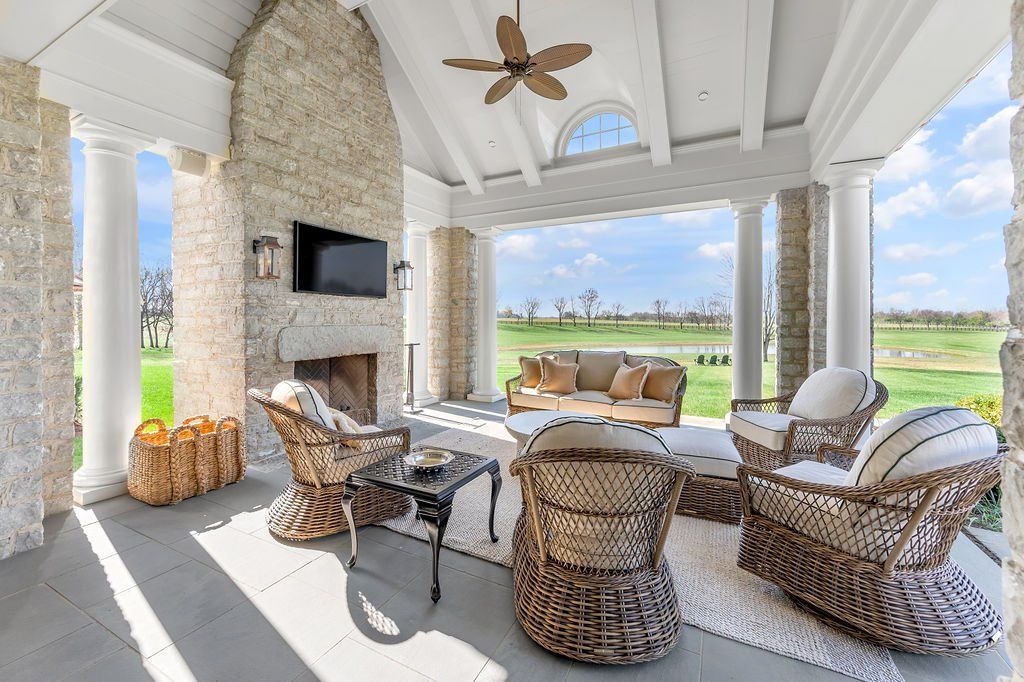 A living room with wicker furniture , a fireplace and a ceiling fan.