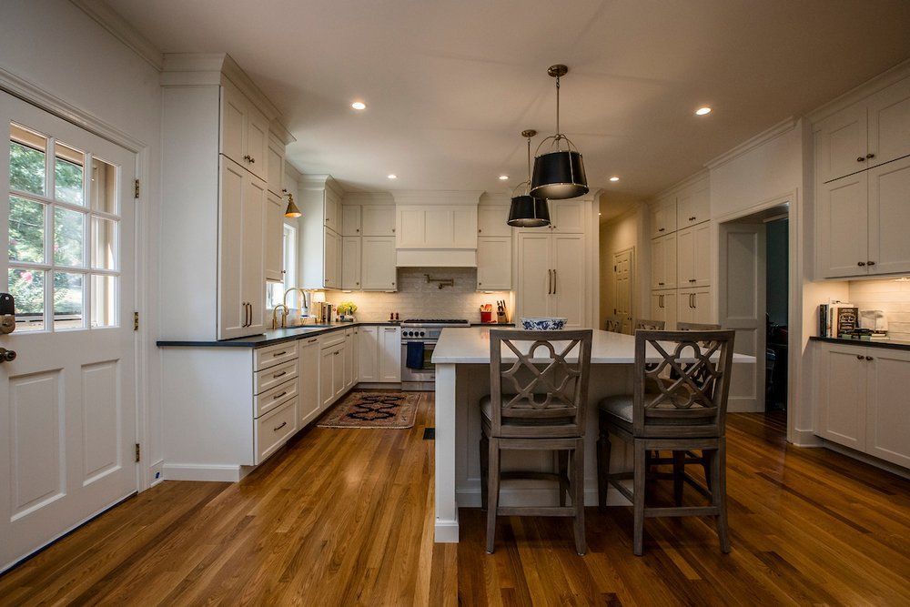 A kitchen with white cabinets and hardwood floors and a large island.
