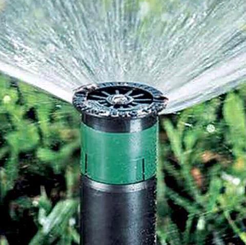 Garden sprinkler spraying water in a green lawn