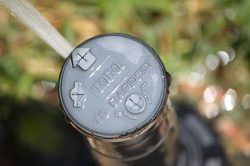 Close-up of a black motorcycle brake fluid reservoir cap with embossed text and screw heads.
