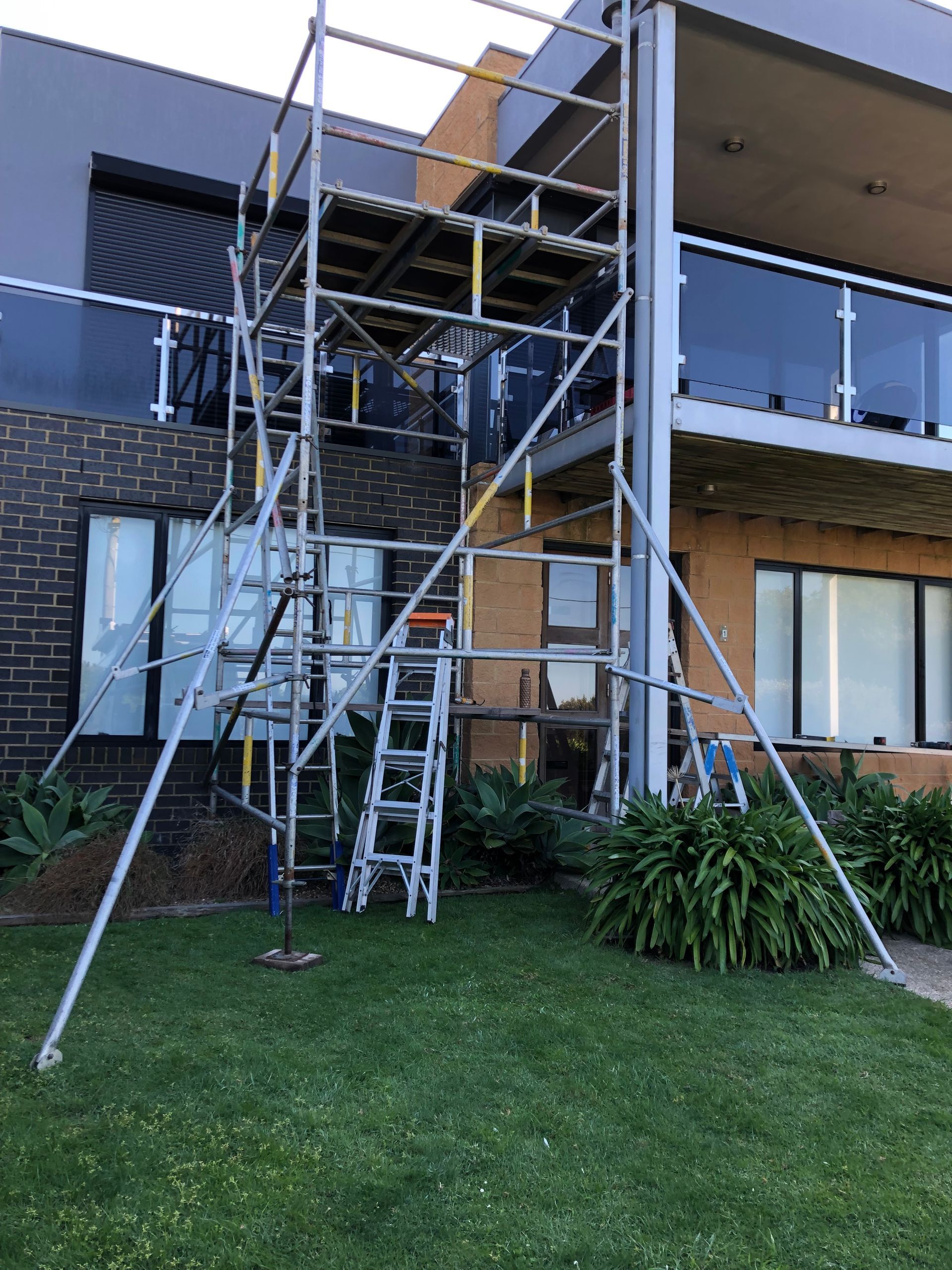 Scaffolding and a ladder set up against an apartment building balcony under construction