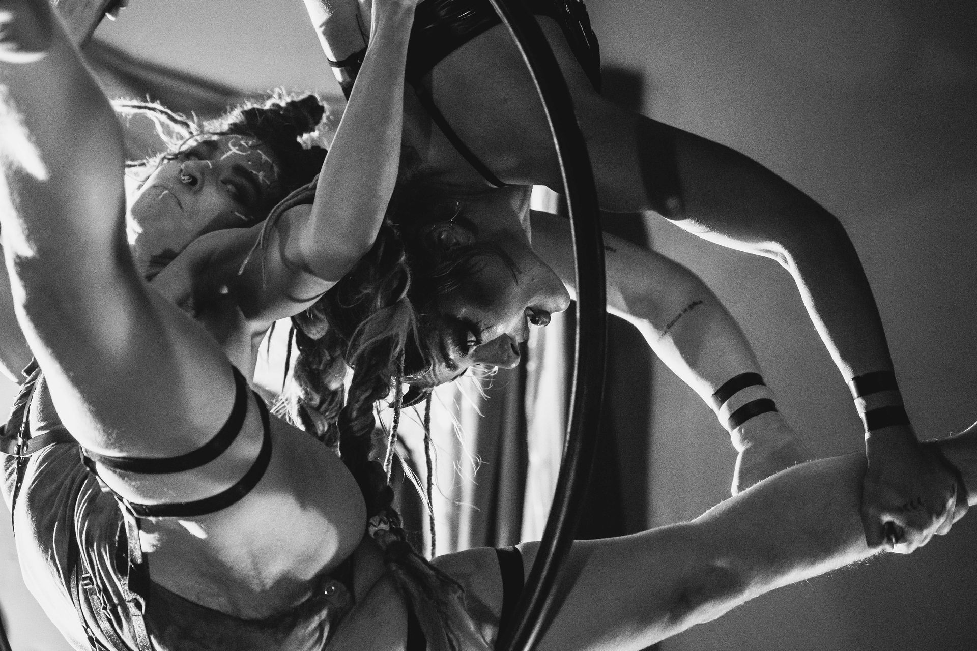 Black and white photo of two female aerial acrobatic performers on a Lyra.