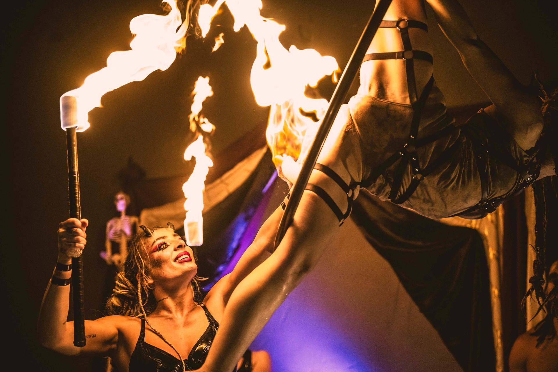 A woman lighting another woman on fire while doing aerial acrobatics.