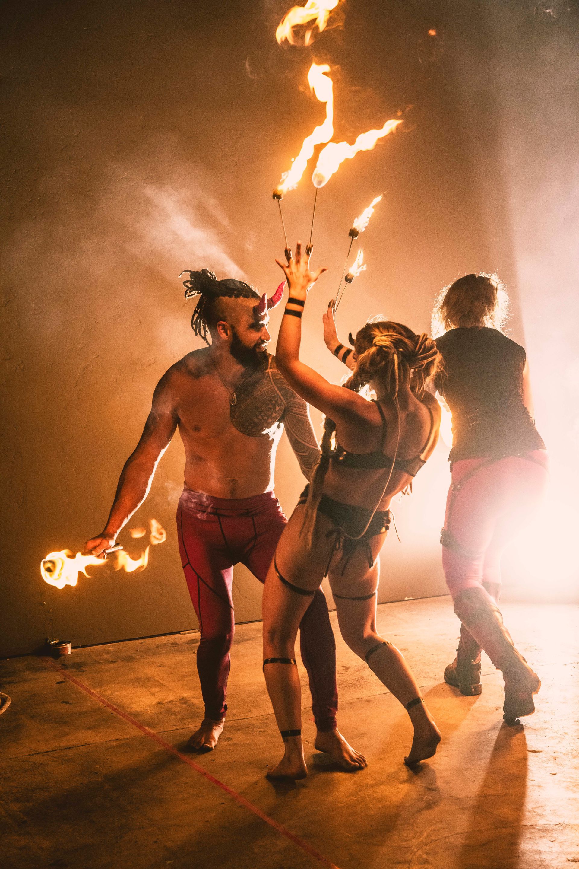A group of people are dancing with fire in a dark room.