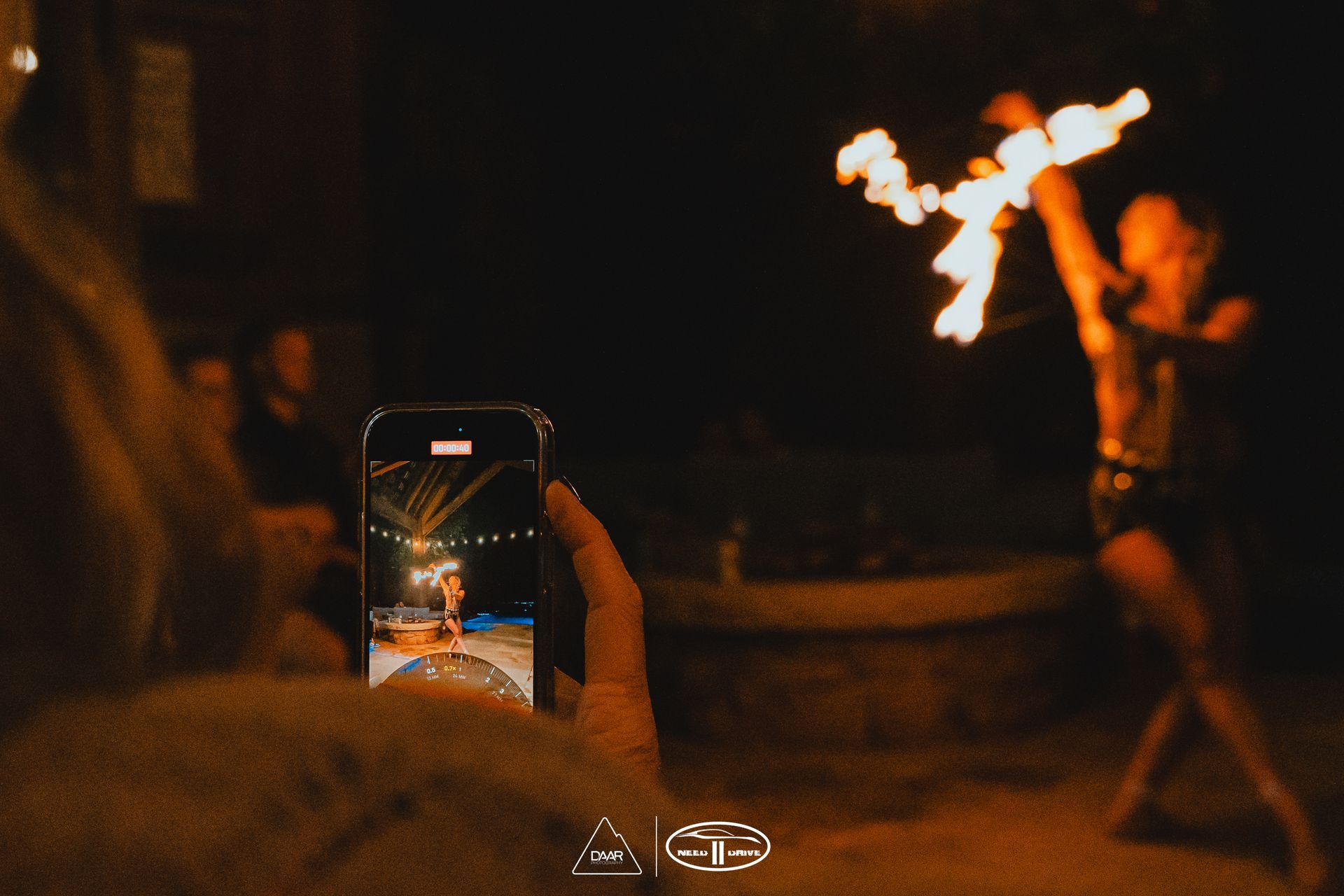 A person is taking a picture of a fire show with a cell phone.