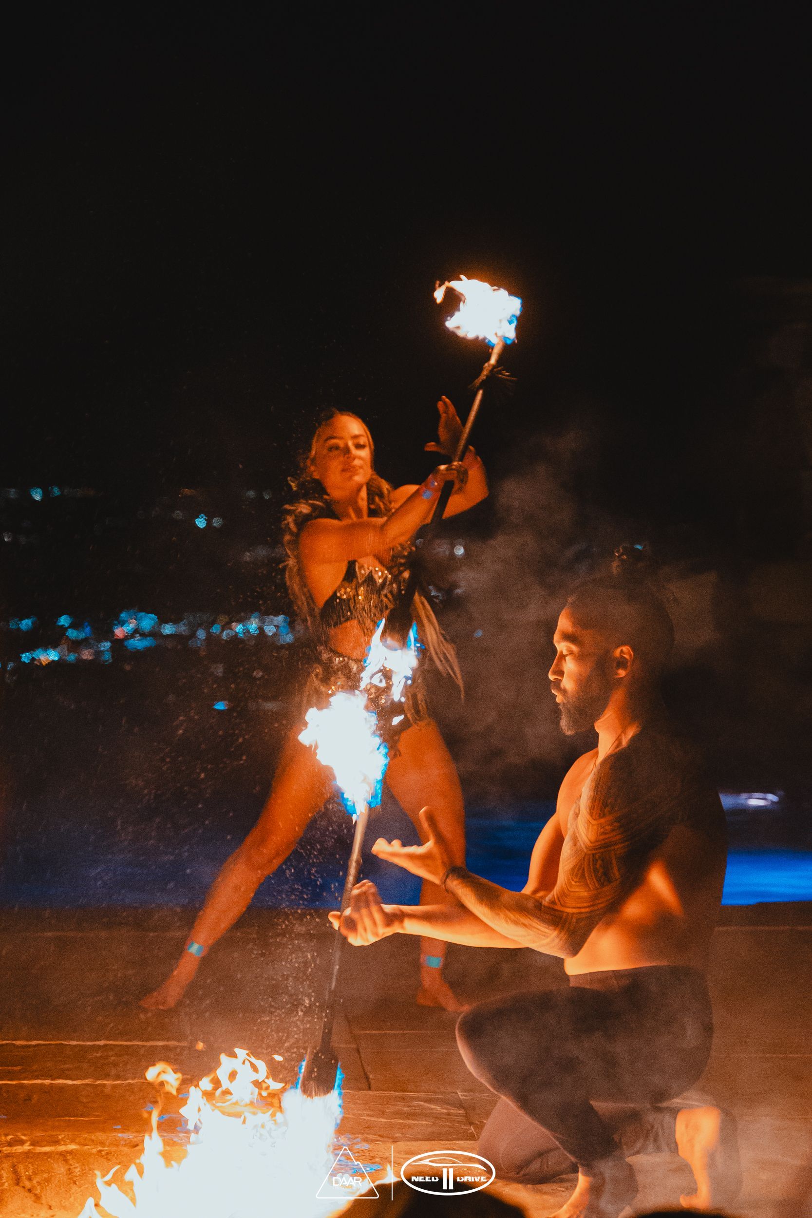 A man and a woman are playing with fire at night.