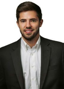A man in a suit and white shirt is smiling for the camera.