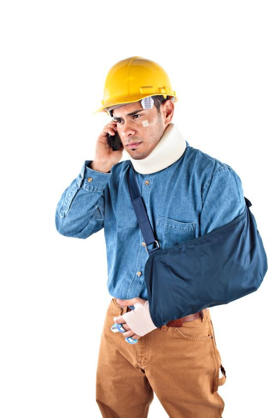 A construction worker with a broken arm is talking on a cell phone.