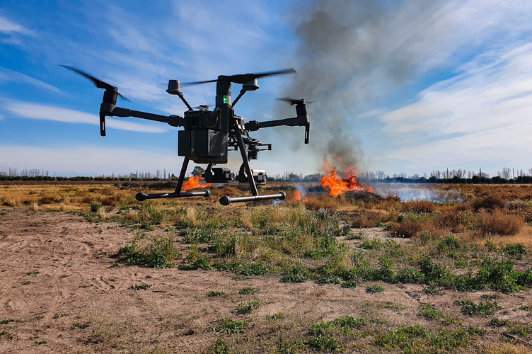 A drone is flying over a field at sunset.