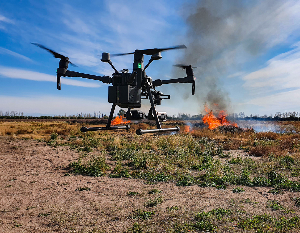 A drone is flying over a field at sunset.