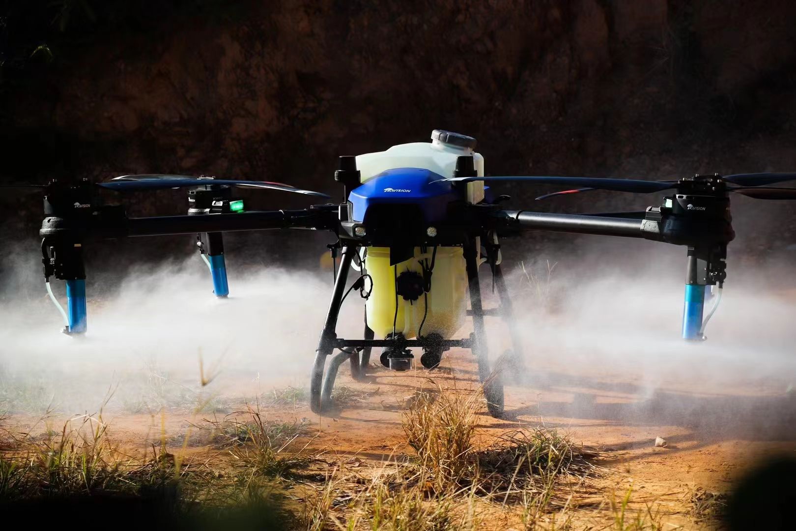 A red drone is flying in the sky over a field