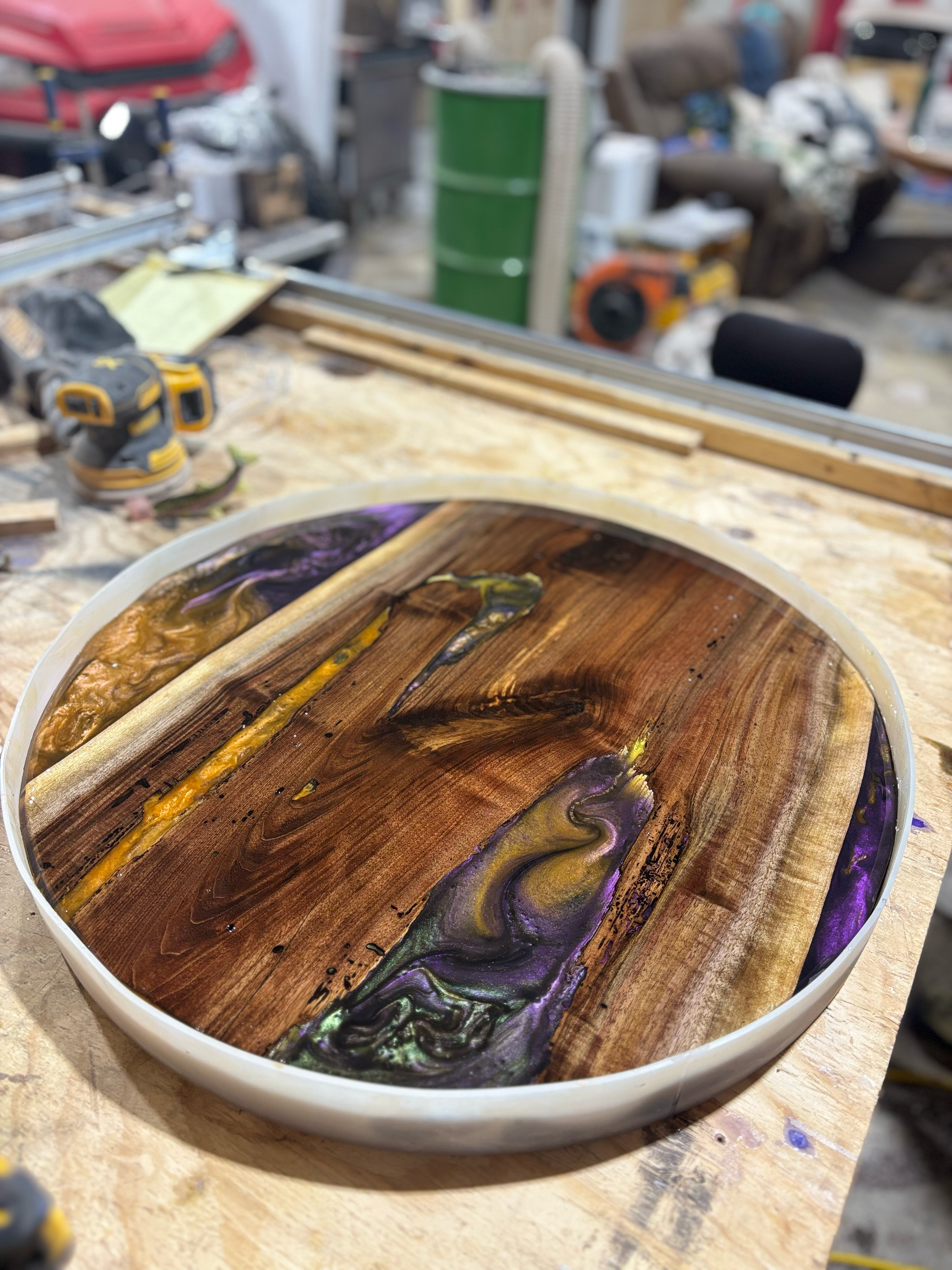 A wooden tray with purple and yellow resin on it is sitting on top of a wooden table.