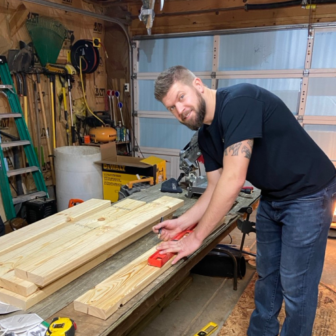 Jordan Timmerman, owner of Timmberman's Woodworking, working on a piece of wood in a garage