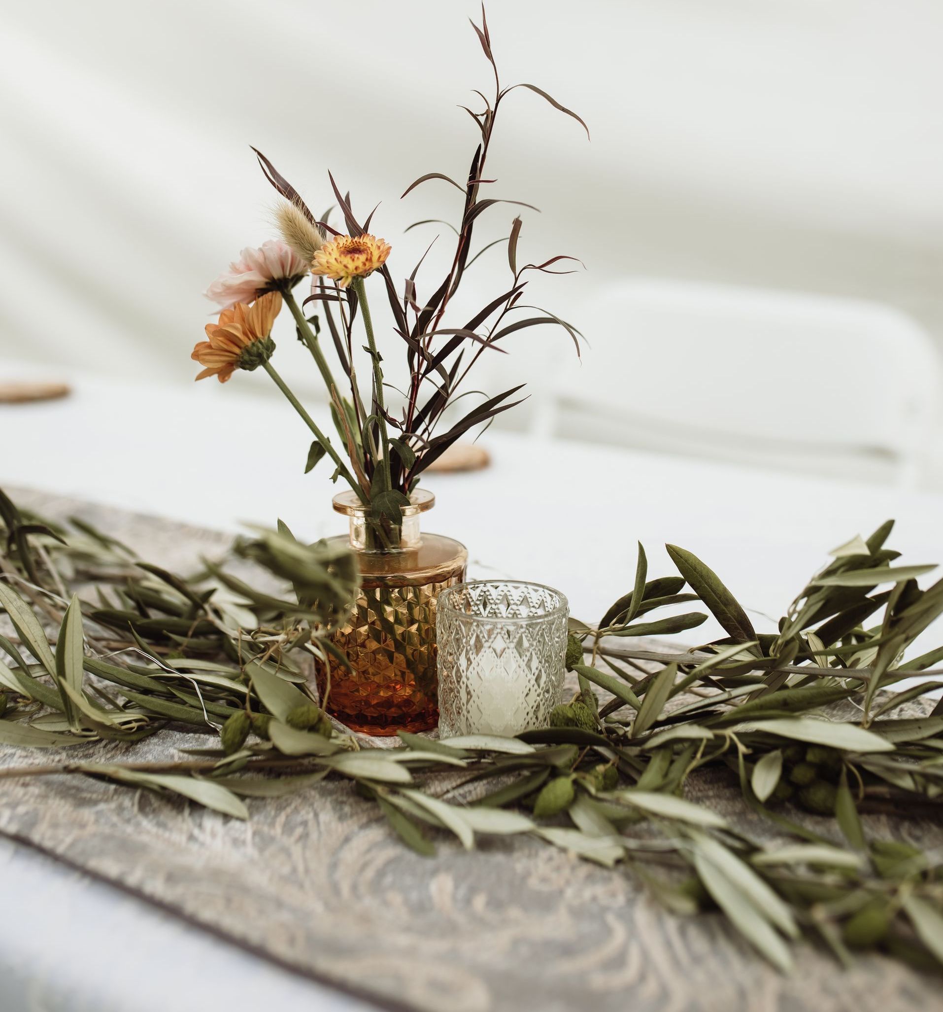 A table with a vase of flowers and a candle on it