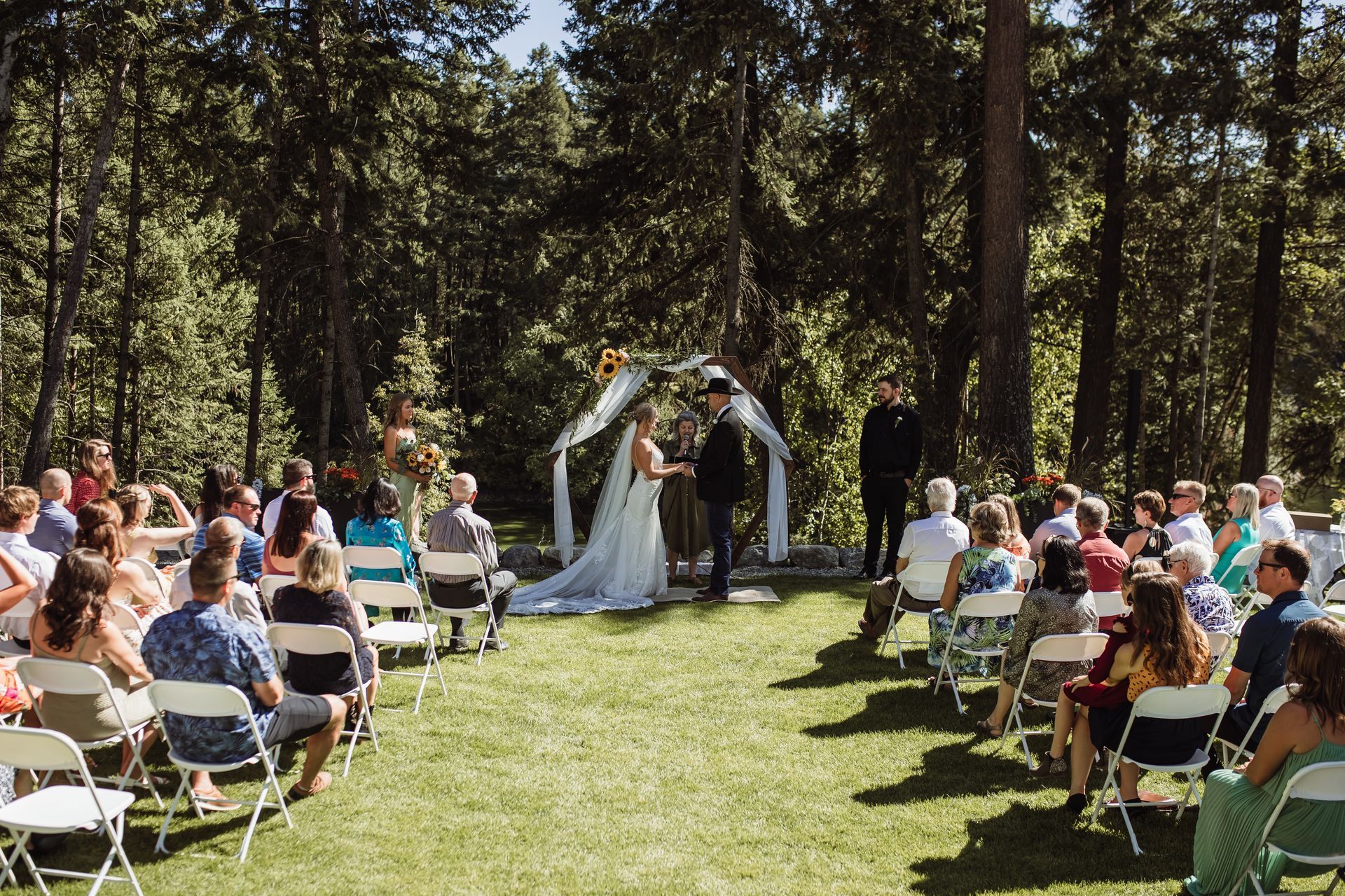 A bride and groom are getting married in front of a crowd of people sitting in folding chairs.