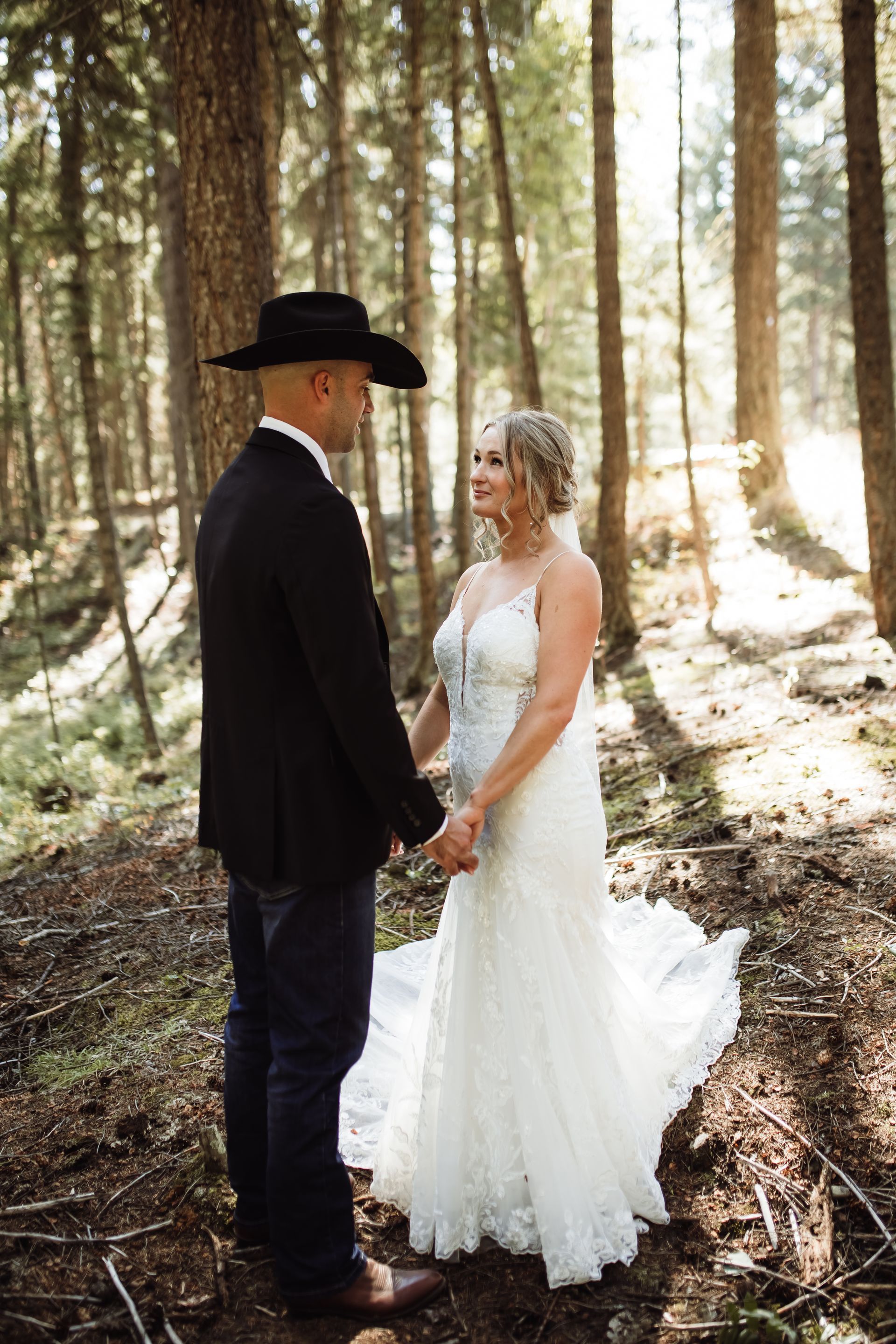 A bride and groom are holding hands in the woods.