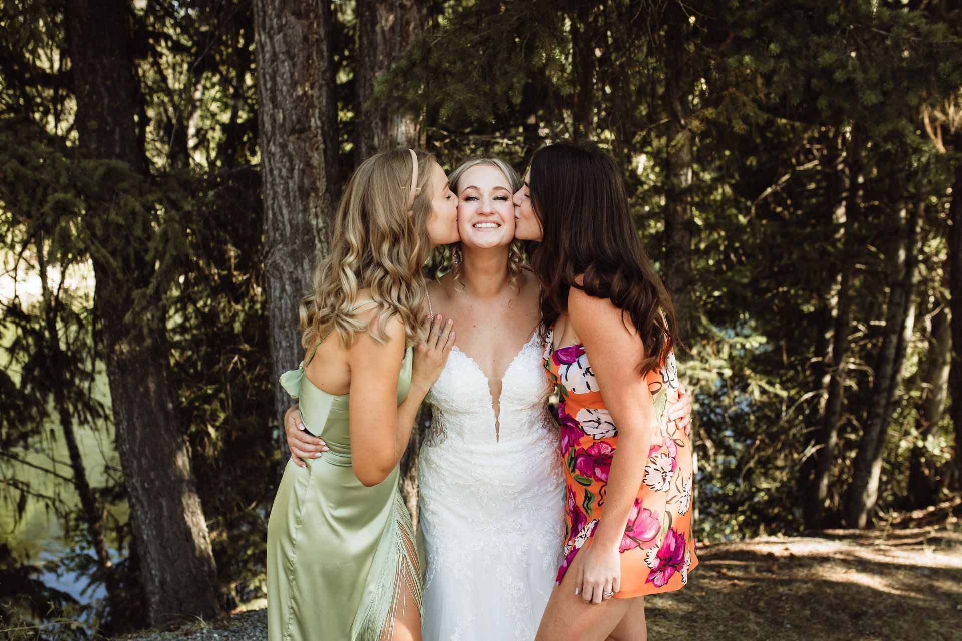 A bride and her two bridesmaids are posing for a picture in the woods.