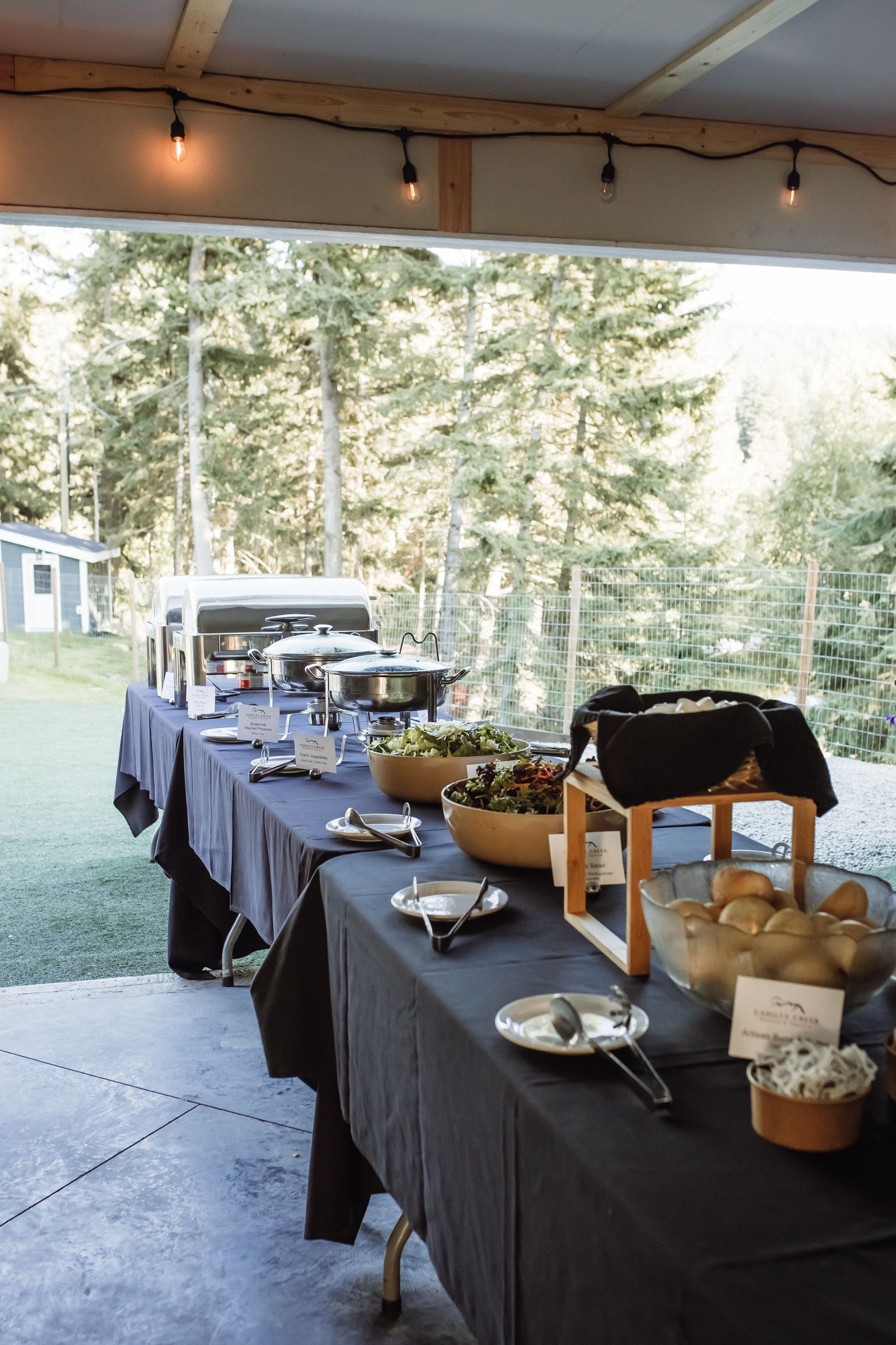 A long table with plates and bowls of food on it.