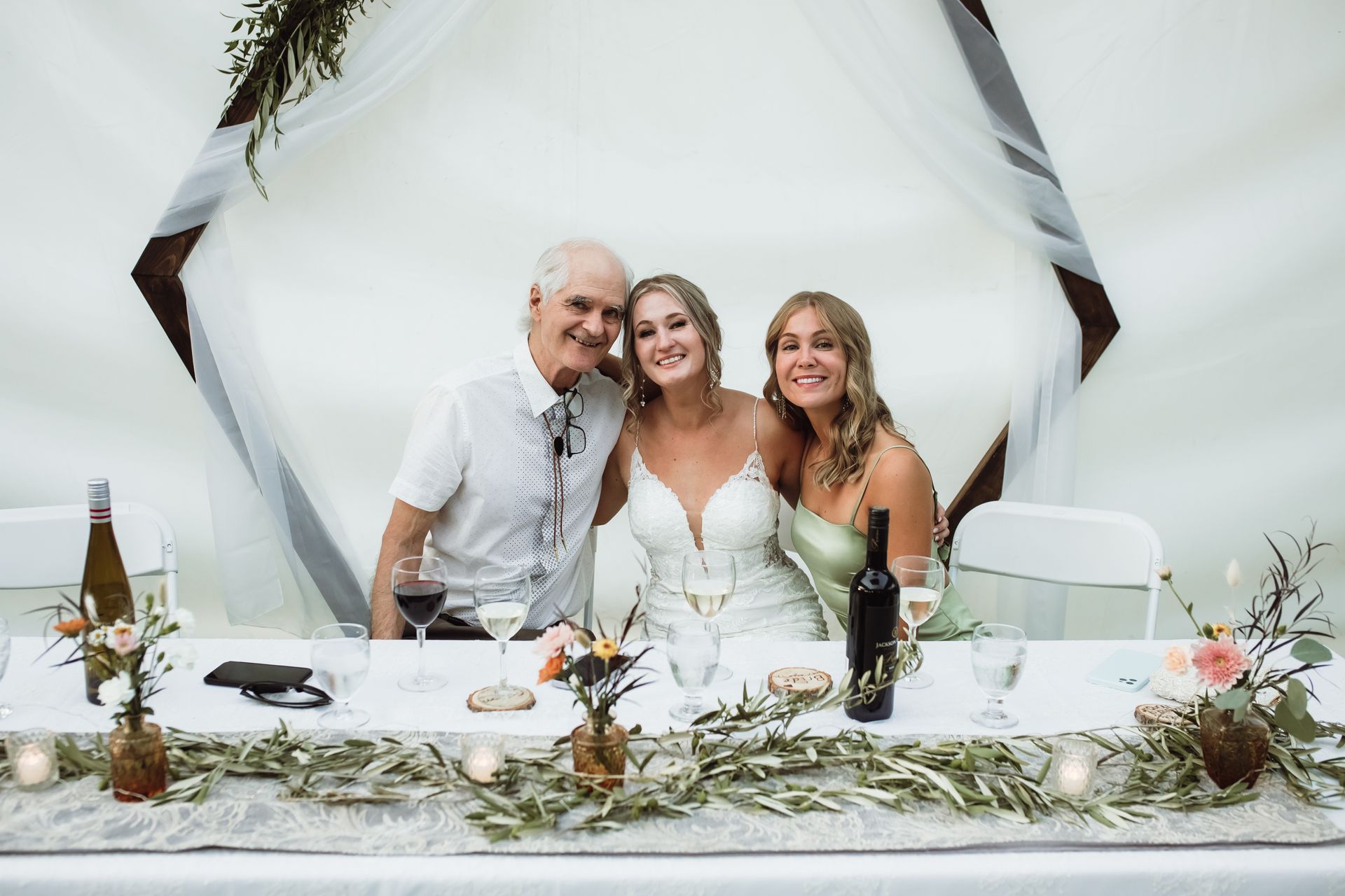 A bride and groom are posing for a picture with their parents at their wedding reception.