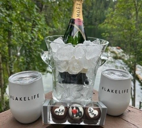 A bottle of champagne is in a bucket of ice next to two wine glasses.