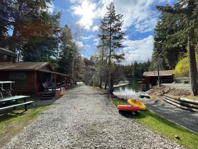 A dirt road leading to a lake with a kayak on the side of it.