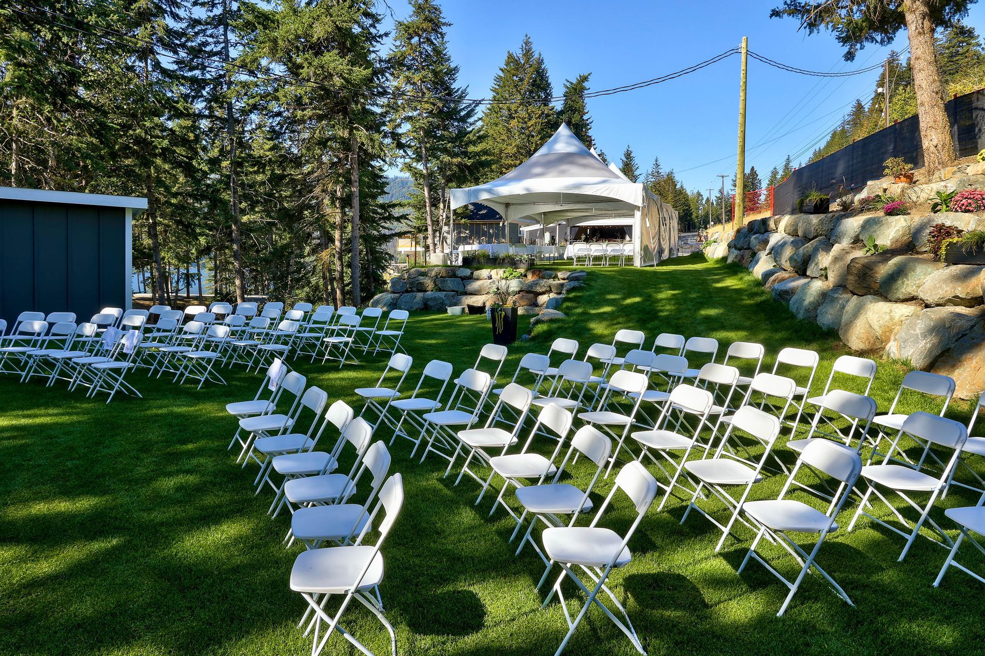 A row of folding chairs are lined up in a grassy field.