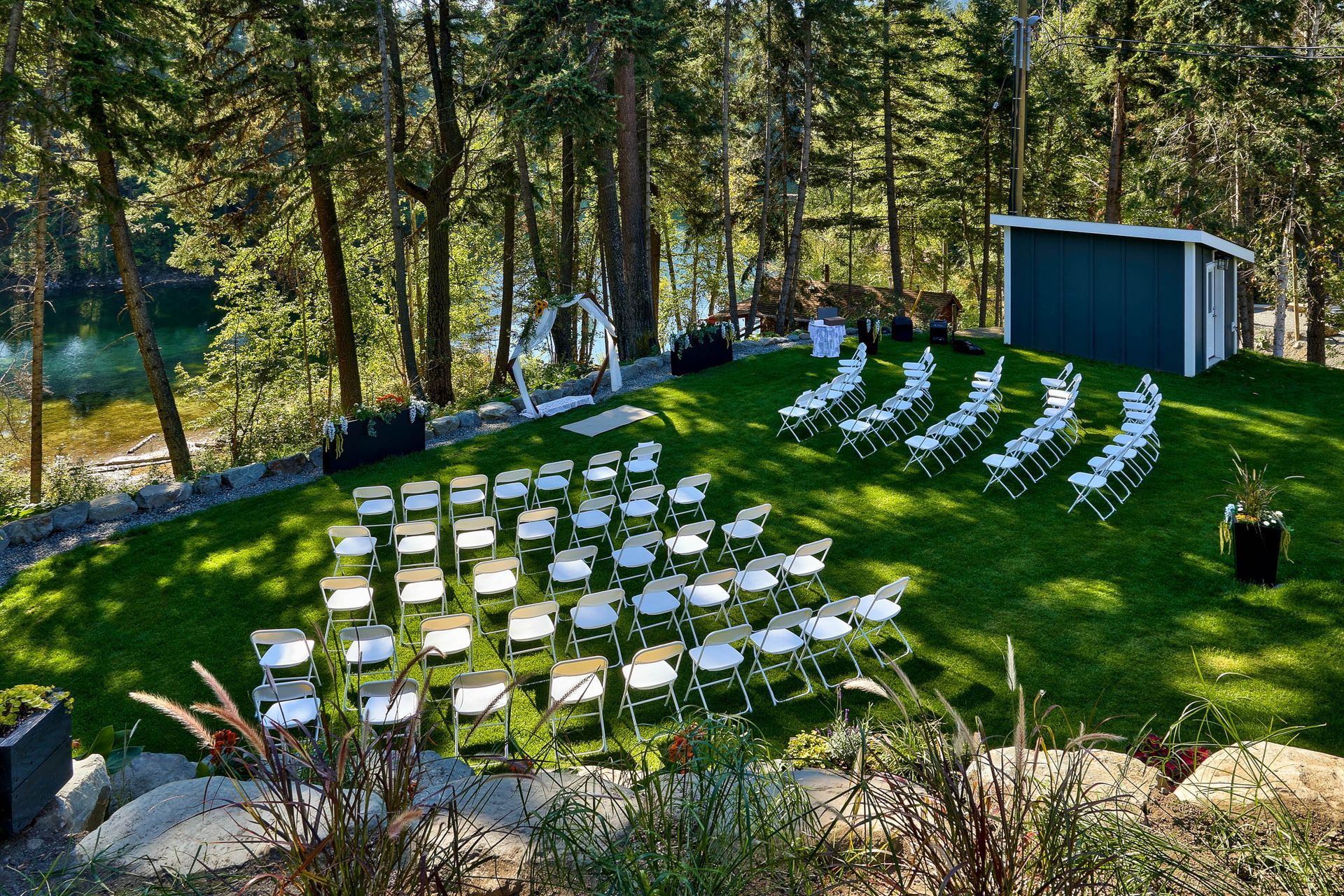 A row of folding chairs are lined up on a lush green field.