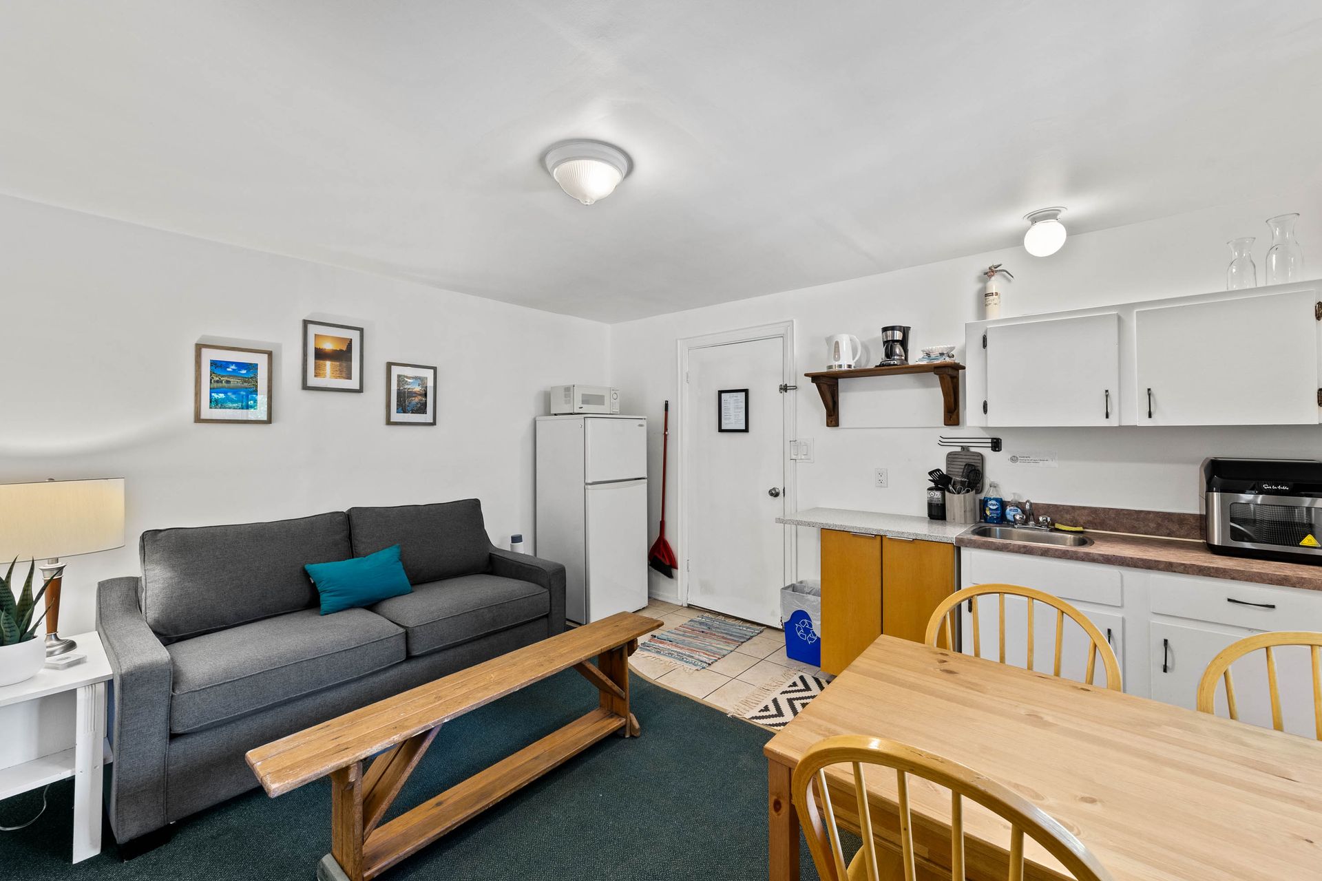 A living room with a couch , table , chairs and a kitchen.
