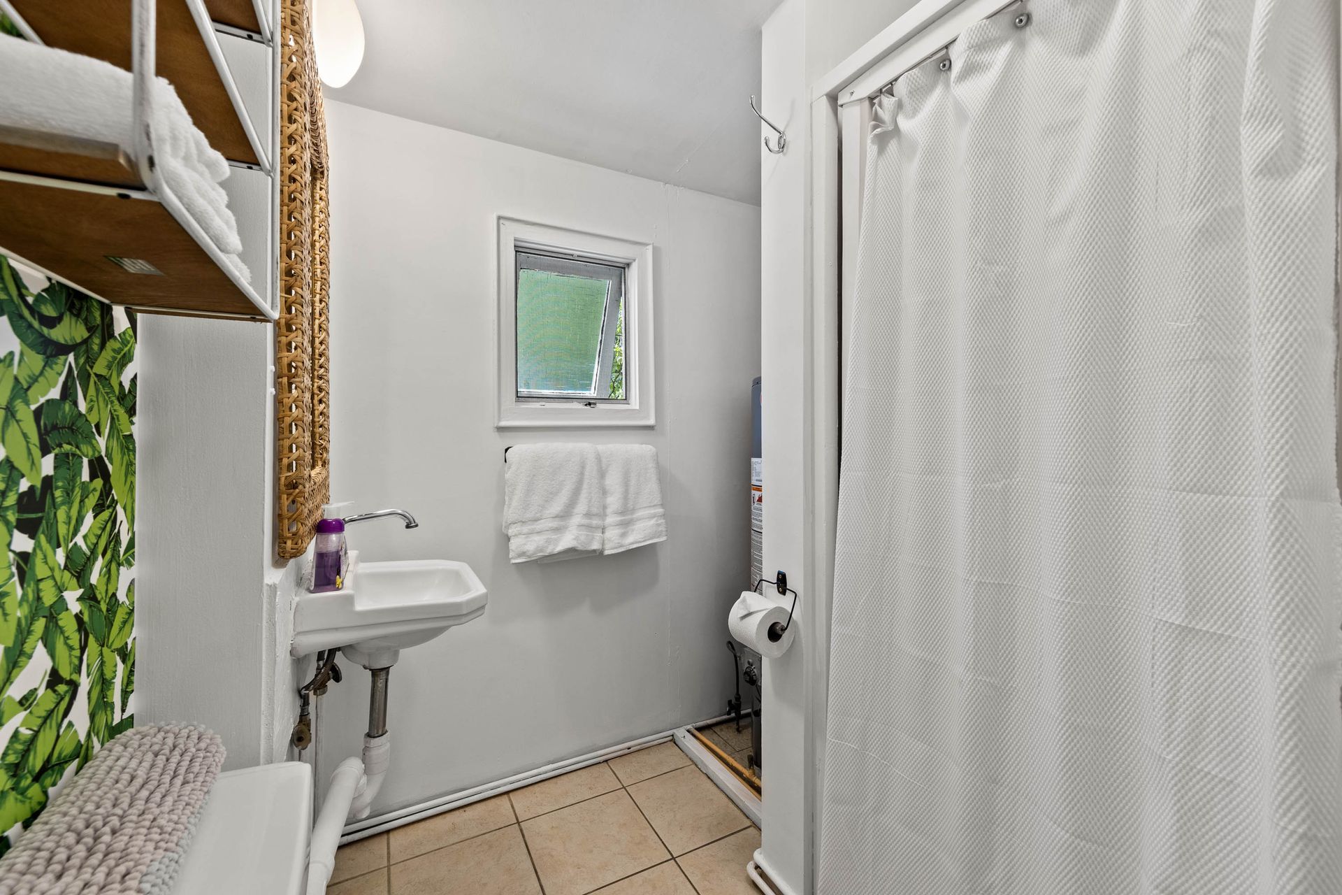 A bathroom with a sink , toilet , shower curtain and mirror.