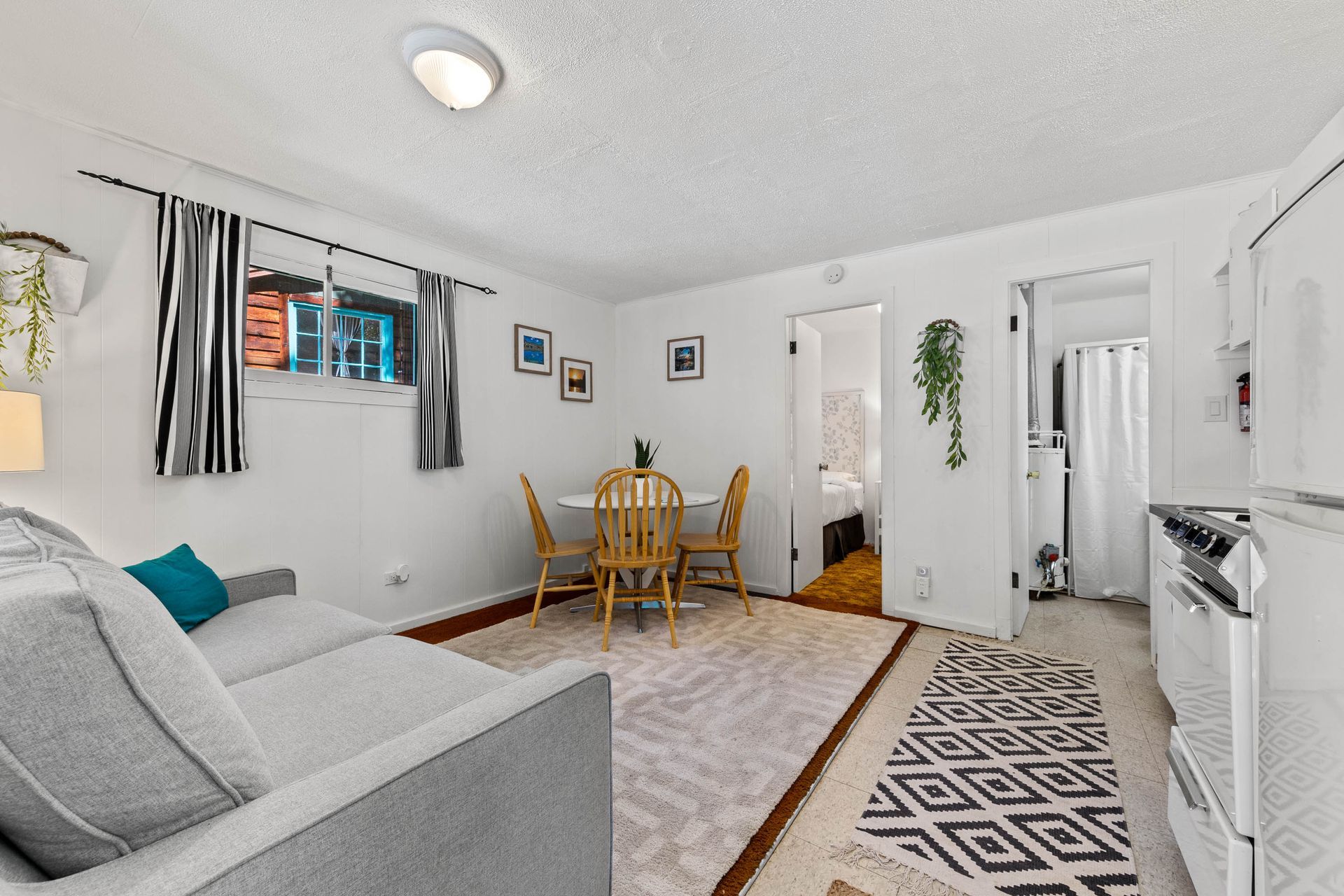 A living room with a couch , table and chairs and a kitchen.