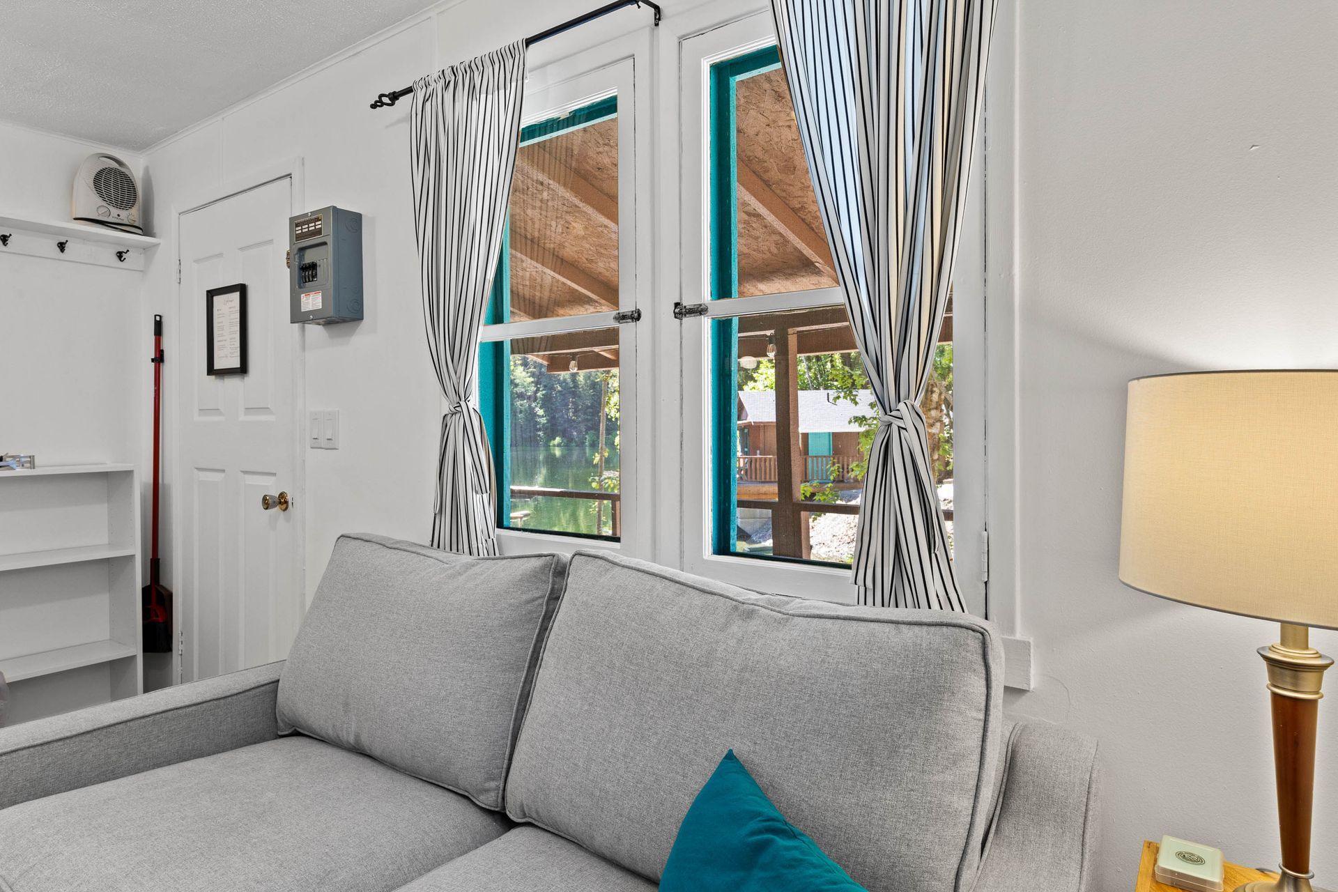 A living room with a couch , lamp , and two windows.