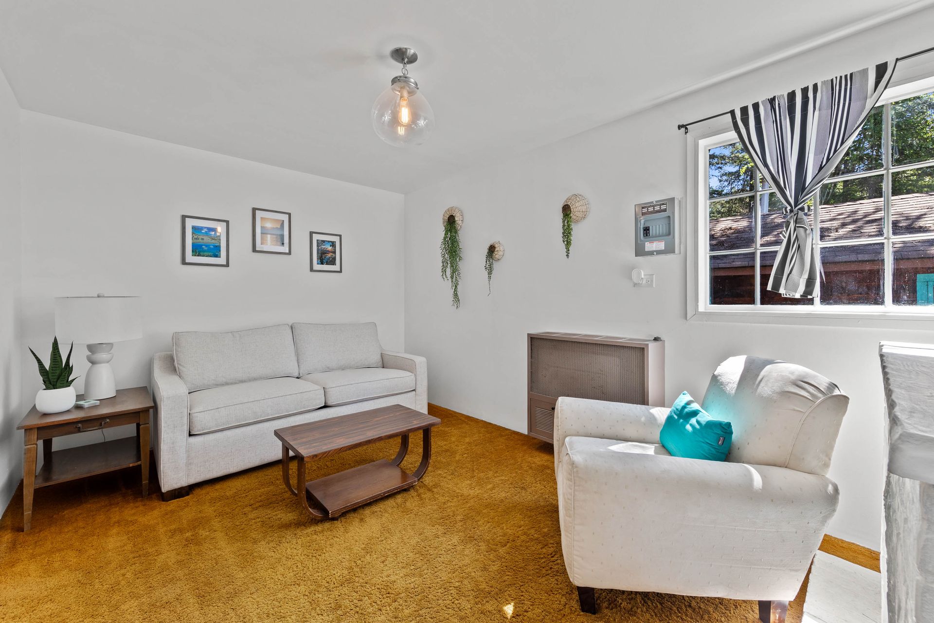 A living room with a couch , chair , coffee table and window.