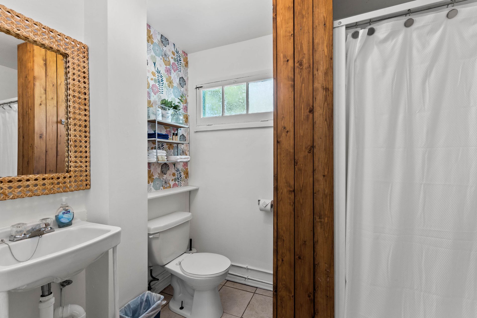 A bathroom with a toilet , sink , mirror and shower curtain.