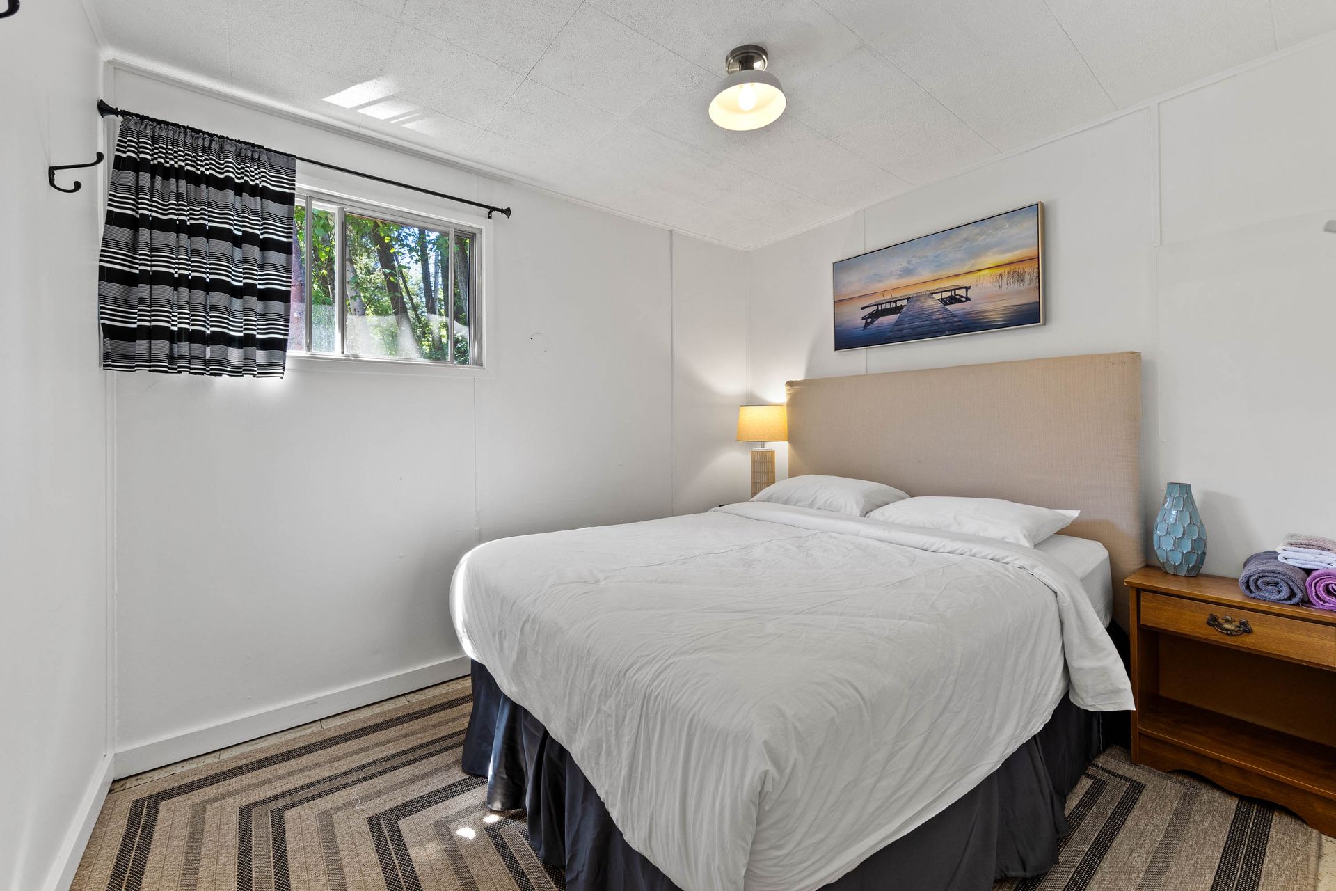 A bedroom with a bed , nightstand , and window.