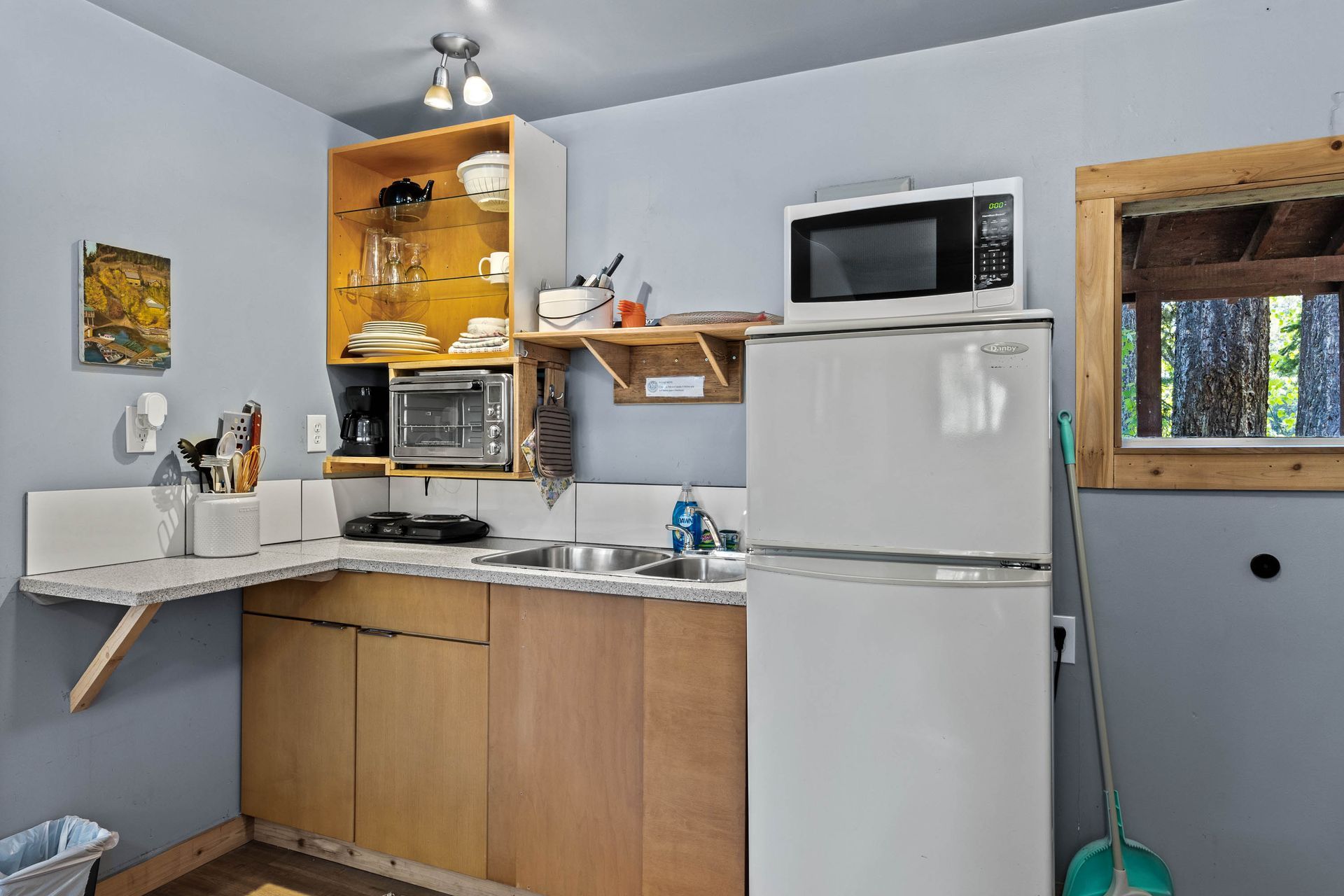 A small kitchen with a refrigerator , microwave , sink and stove.