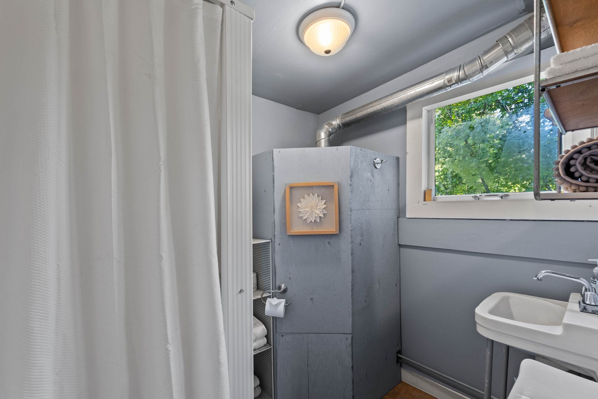 A bathroom with a sink , shower , and window.