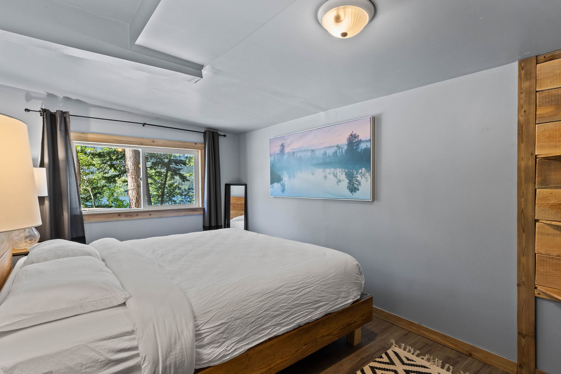 A bedroom with a king size bed and a painting on the wall.