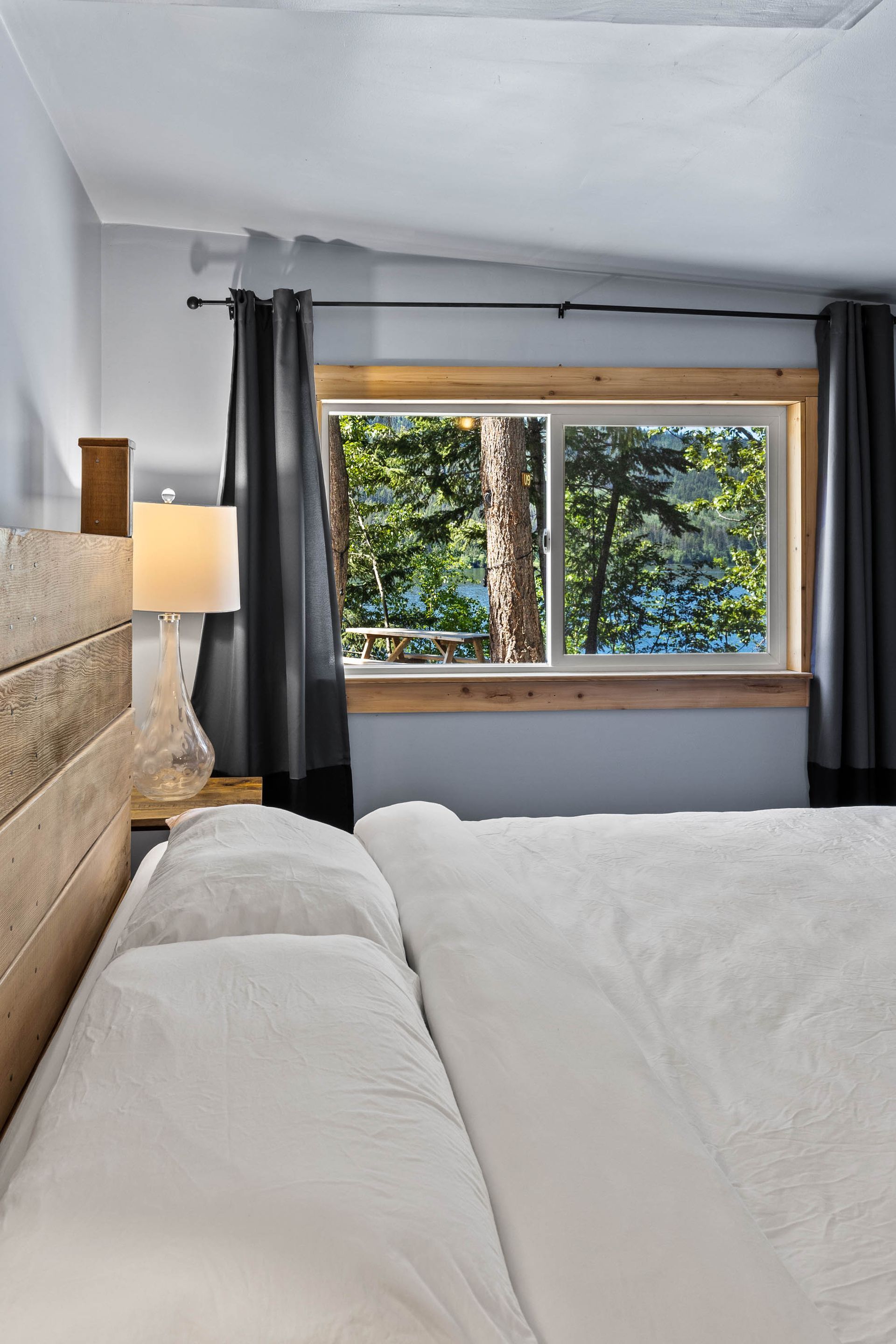 A bedroom with a bed and a window with a view of a lake.